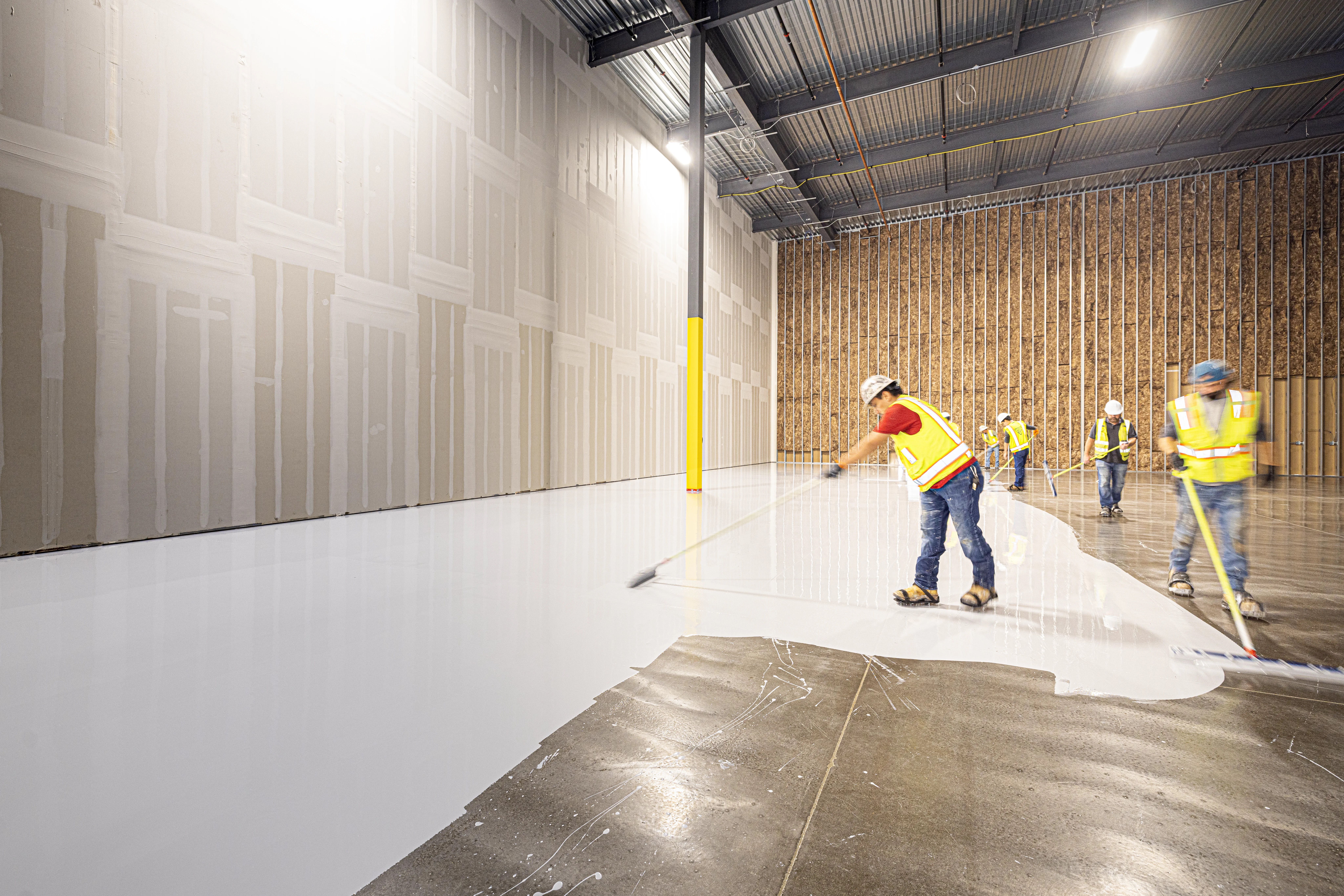 Contractor broadcasting decorative flakes onto a fresh epoxy garage floor coating