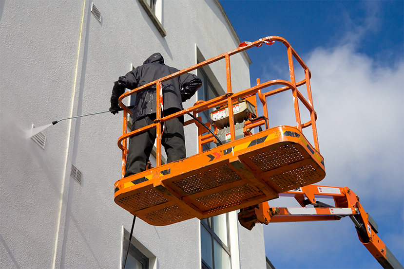Contractor safely soft washing vinyl siding to remove green algae